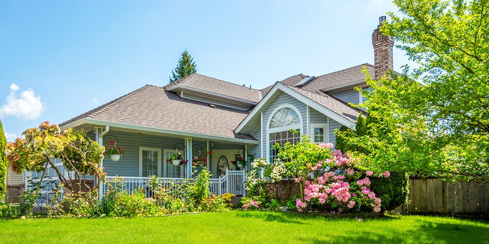 Front of a light-blue suburban house with a covered porch - https://www.rogersvilleins.com/