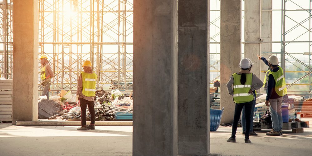 Construction site interior with workers in high-visibility vests - https://www.rogersvilleins.com/